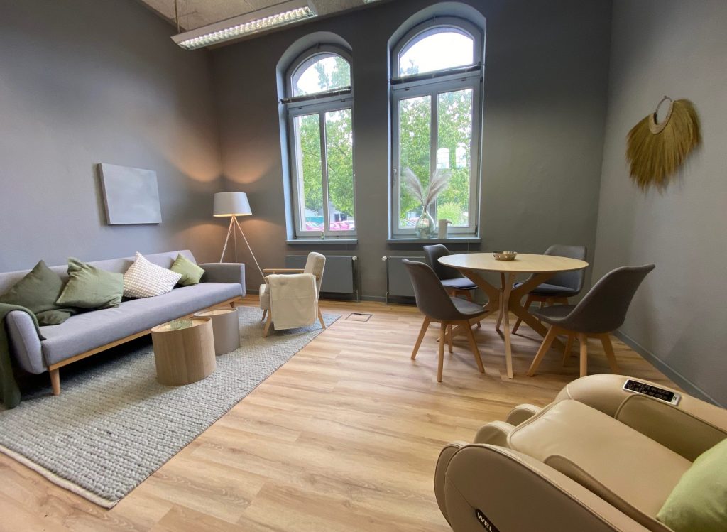 Modernes und einladendes Büro mit bequemer Couch, Stuhl und Tisch für 4 Personen, ideal für gesellige Stunden und mit viel Tageslicht in Moers.